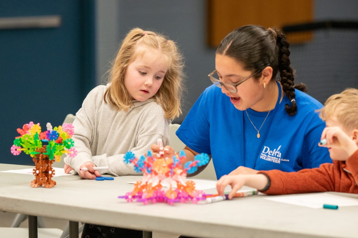 Children work with a volunteer to build a toy at a community recreation program. 