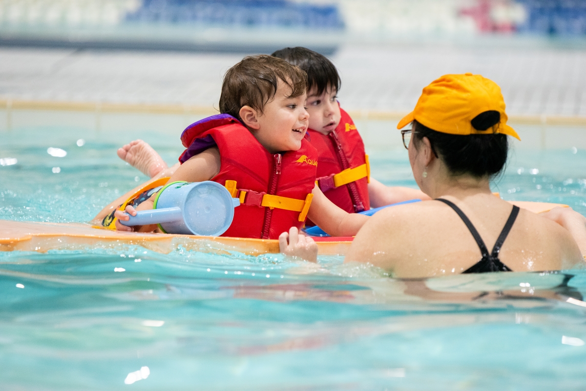 Two students enjoy a mat ride in a swimming lesson at Winskill. 
